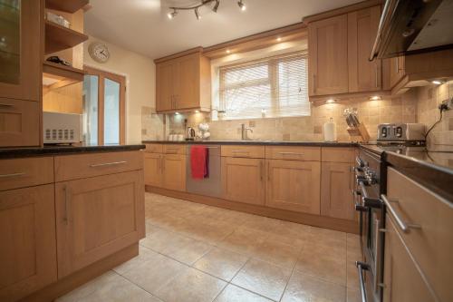 a large kitchen with wooden cabinets and a sink at Goldcrest House by RentMyHouse in Hereford