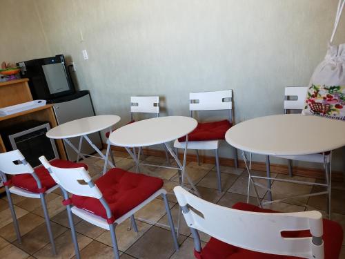 a room with white tables and red chairs at SkyView Swift Current in Swift Current