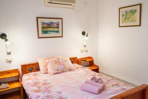 a bedroom with a bed with pink sheets and purple towels at House On The Mountain in Neve Ativ