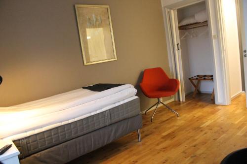 a bedroom with a bed and a red chair at Lindesbergs Stadshotell in Lindesberg