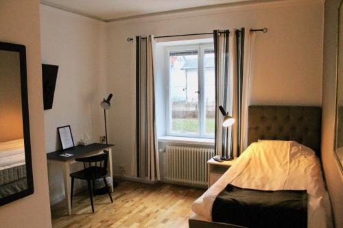 a bedroom with a bed and a window and a desk at Lindesbergs Stadshotell in Lindesberg