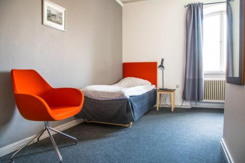a bedroom with a bed and a chair in it at Lindesbergs Stadshotell in Lindesberg
