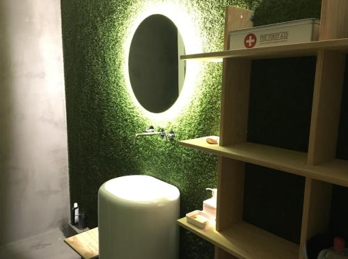 a bathroom with a green wall with a round mirror at LUZZ me - Casa de Angra in Angra do Heroísmo