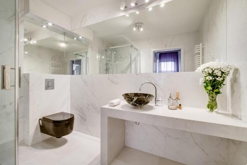 a white bathroom with a sink and a mirror at SAVOY Mariacka Apartments in Katowice