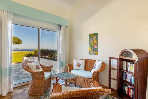 - un salon avec des chaises en osier et une étagère dans l'établissement Hotel Luna Lughente, à Olbia