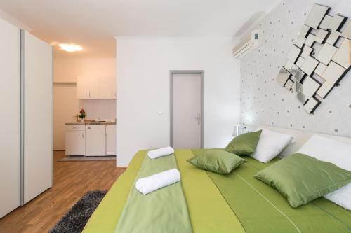 a bedroom with a large green bed with white pillows at Villa Voinic 2 in Cavtat