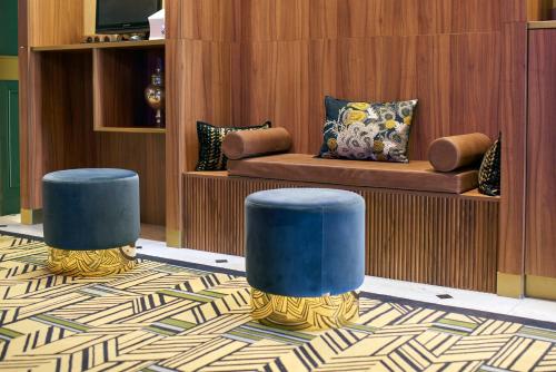 a living room with two blue stools and a couch at Hotel Konti Bordeaux by HappyCulture in Bordeaux