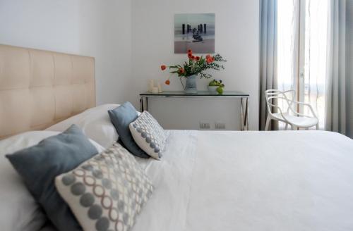 ein Schlafzimmer mit einem weißen Bett mit Kissen darauf in der Unterkunft Agora Apartments in Sorrent