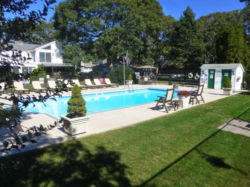 a swimming pool in a yard with chairs and a house at Falmouth Heights Motor Lodge in Falmouth