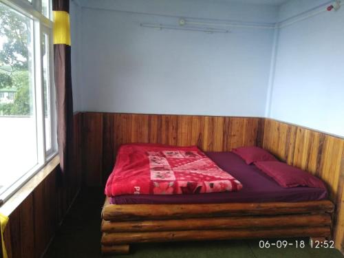 a bed with a red comforter in a room at Vamoose Cosynook Homestay in Takdāh