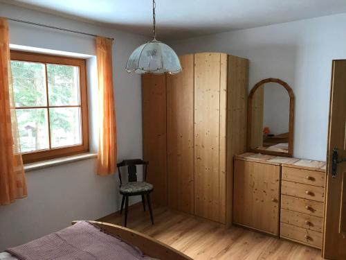 ein Schlafzimmer mit einem Bett, einem Spiegel und einem Stuhl in der Unterkunft Ferienhaus Dorfblick in Außervillgraten