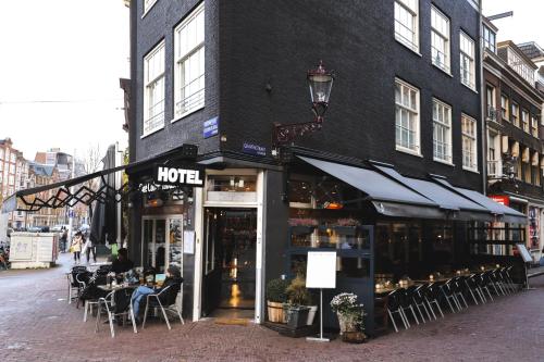 ein Café mit Leuten, die vor einem Gebäude an Tischen sitzen in der Unterkunft Hotel Corner House in Amsterdam