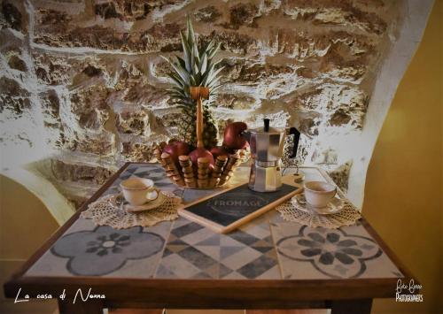 a table with a bowl of fruit and cups on it at La Casa di Nonna in Tivoli