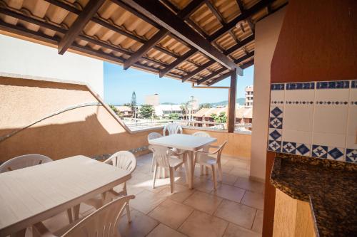 a patio with tables and chairs and a view of the ocean at Pousada Lugar ao Sol in Bombinhas