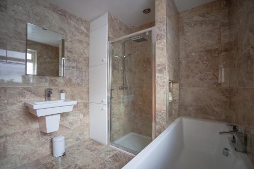 een badkamer met een douche, een bad en een wastafel bij Goldcrest House by RentMyHouse in Hereford