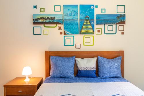 una camera da letto con un letto con cuscini blu e quadri appesi al muro di Apartamento Serramar , Vistas deslumbrantes a Calheta