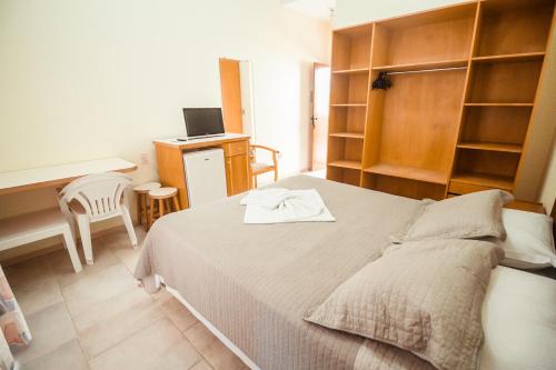 a bedroom with a bed and a desk and a computer at Pousada Lugar ao Sol in Bombinhas
