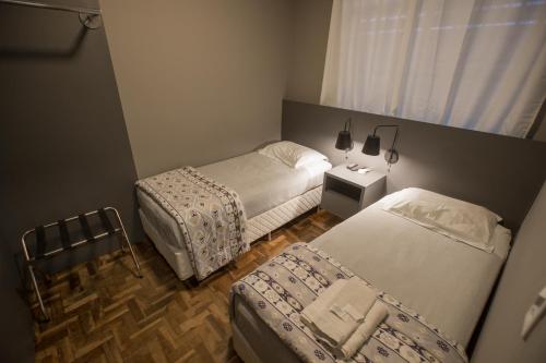 a small bedroom with two beds and a window at Ipê Hotel Express in Ponta Grossa
