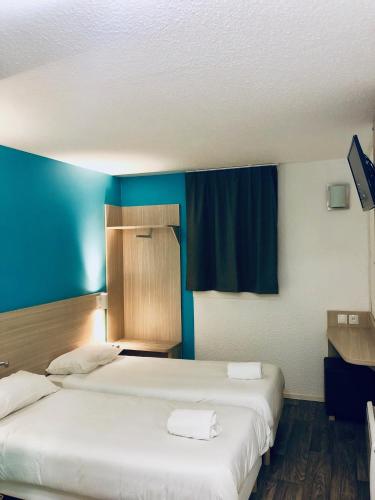 two beds in a room with blue walls at Hôtel du stade ex Kyriad Direct Lille Est Stade Pierre Mauroy in Villeneuve d'Ascq