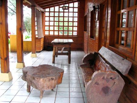 um quarto com um banco, uma mesa e janelas em Cabañas Lupita 31 em Mazamitla