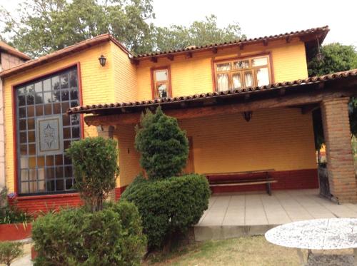 a yellow house with a bench in front of it at Cabañas Lupita 31 in Mazamitla