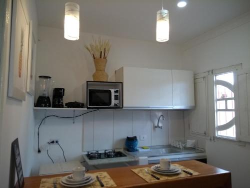 una cucina con un microonde e un tavolo con i piatti di Flat Porto a Porto De Galinhas