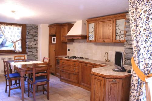 una cucina con armadi in legno e un tavolo con televisore di Maison Chante Lune a Introd