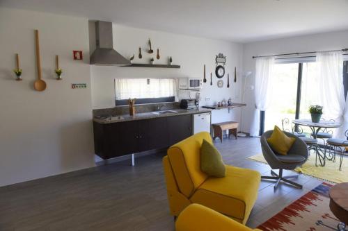 a living room with a yellow chair and a kitchen at Casa dos Becos in Riba Douro