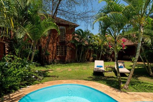 a pool in a yard with two chairs and a house at Kili Villa Kilimanjaro Luxury Retreat in Arusha