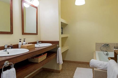 a bathroom with two sinks and a mirror and a tub at Kili Villa Kilimanjaro Luxury Retreat in Arusha