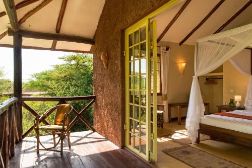 a bedroom with a bed and a balcony at Kili Villa Kilimanjaro Luxury Retreat in Arusha