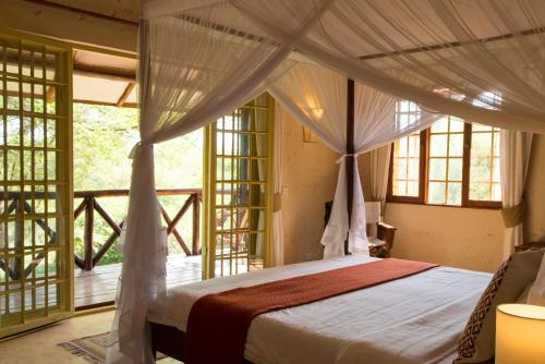 a bedroom with a canopy bed and a balcony at Kili Villa Kilimanjaro Luxury Retreat in Arusha