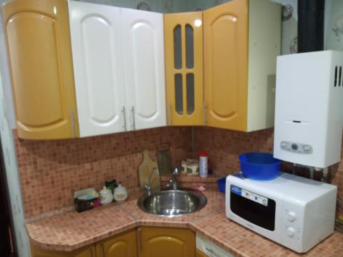 エレツにあるApartment on Kostenko 44аのキッチン(黄色のキャビネット、シンク、電子レンジ付)