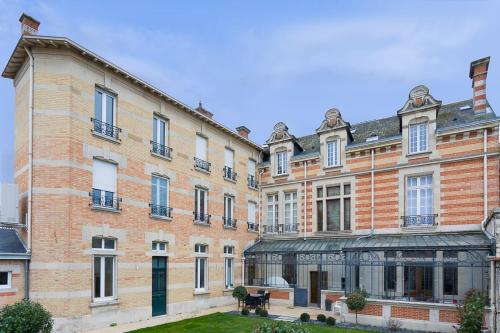 een groot bakstenen gebouw met een tafel ervoor bij Le Jardin d'Hiver in Châlons-en-Champagne