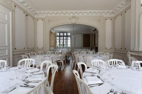une salle remplie de tables blanches et de chaises blanches dans l'établissement Le Jardin d'Hiver, à Châlons-en-Champagne