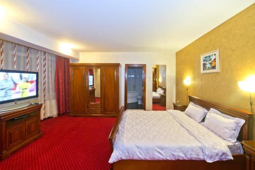 a hotel room with a bed and a flat screen tv at Hotel Bavaria in Craiova