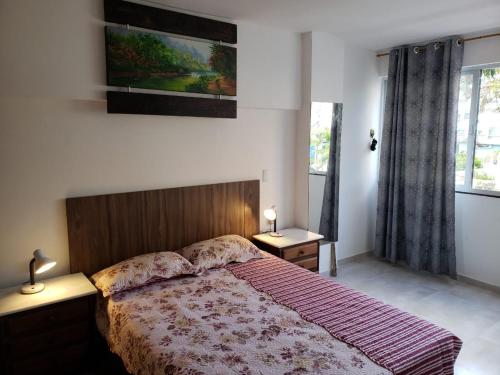 a bedroom with a bed and two tables and a window at Confortável 2 Quartos Castanheiras in Guarapari