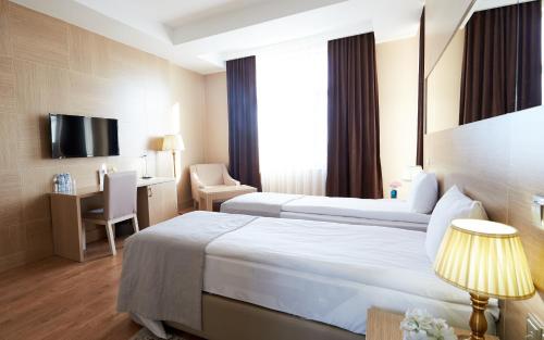 a hotel room with two beds and a desk at NOBEL Hotel in Baku