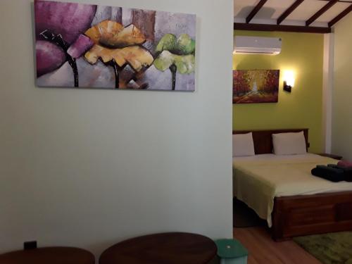 a bedroom with a bed and a painting on the wall at Karl Holiday Bungalow in Kalutara