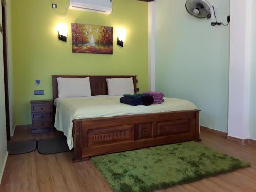 a bedroom with a bed with a green wall at Karl Holiday Bungalow in Kalutara