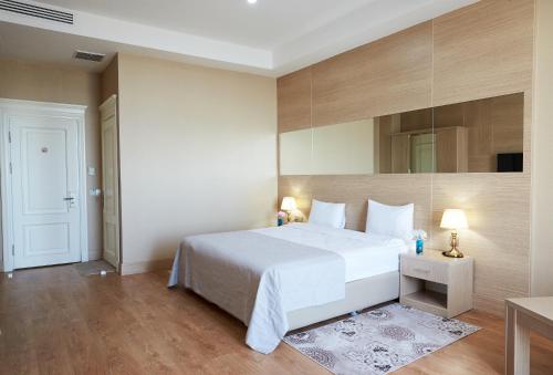 a bedroom with a large white bed and a mirror at NOBEL Hotel in Baku