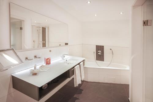 a white bathroom with a sink and a bath tub at Hotel Restaurant Der Engel, Sasbachwalden in Sasbachwalden