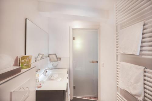 a white bathroom with a sink and a mirror at Hotel Restaurant Der Engel, Sasbachwalden in Sasbachwalden