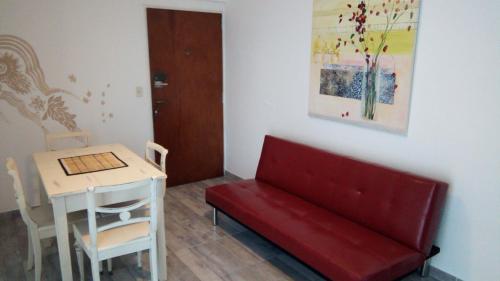 Una sala de estar con un sofá rojo y una mesa. en Apartamento La Loca del Pincel, en Buenos Aires