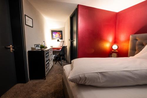 a bedroom with a red headboard and a desk at Engel Hotel + Diner in Aulendorf