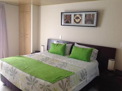 a bedroom with a large bed with green pillows at Hoteles Bogotá Inn El Lago Country in Bogotá