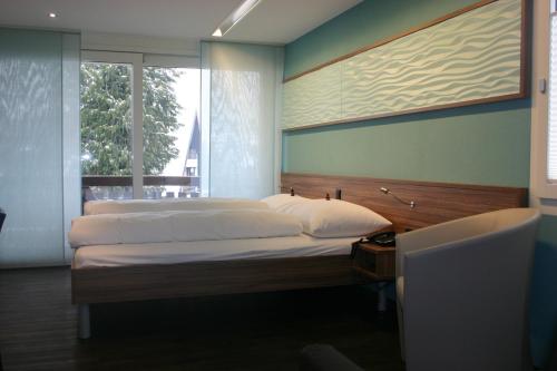 a bedroom with two beds and a large window at Superior Hotel Nidwaldnerhof in Beckenried