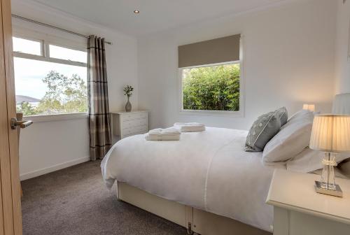 una camera bianca con un grande letto con due finestre di Loch Broom Cabins Seaviews& Petfriendly a Leckmelm