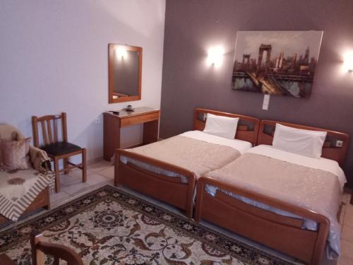 a bedroom with two beds and a chair and a mirror at Zisis Garden Studios in Ioannina