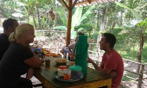 a group of people sitting around a wooden table at Tereng Wilis Jungle Inn in Tetebatu